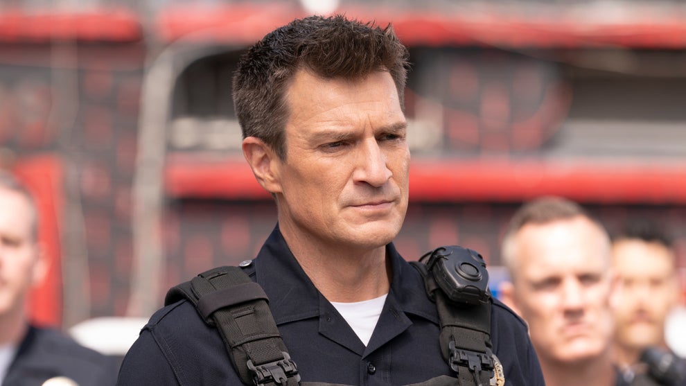 Nathan Fillion wears combat gear and looks out of frame