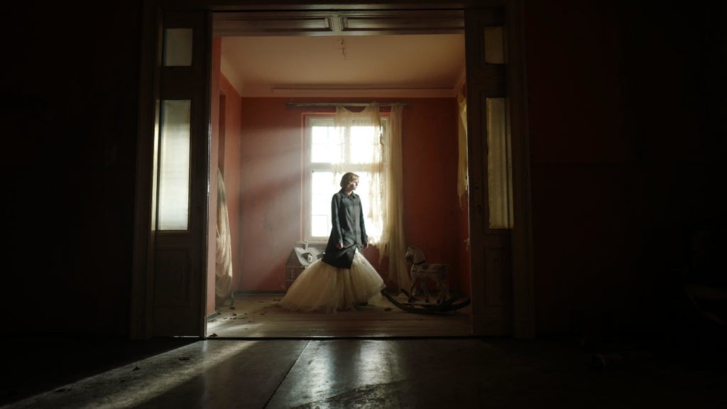 Kristen Stewart stands next to a window in "Spencer."