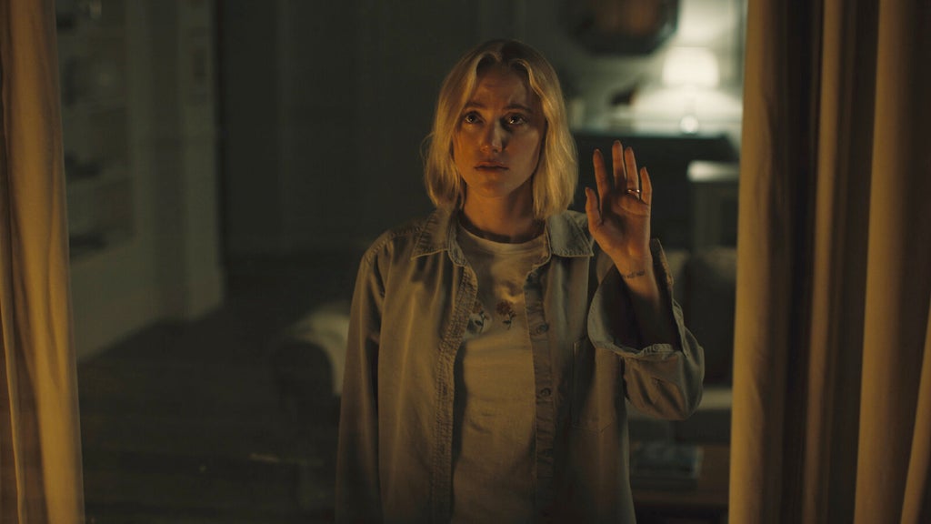Maika Monroe presses her hand against a window in "Watcher."