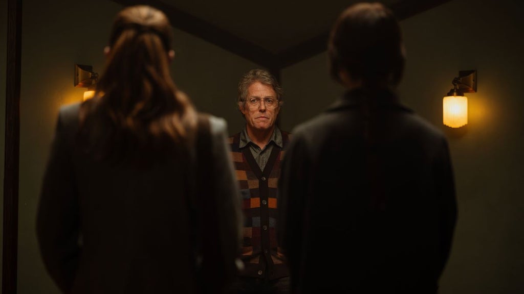 Hugh Grant stands between Chloe East and Sophie Thatcher in "Heretic."