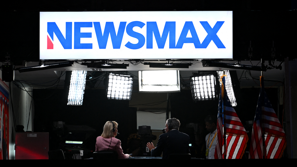 News anchors work at Newsmax's booth during the second day of the 2024 Republican National Convention at the Fiserv Forum in Milwaukee, Wisconsin, July 16, 2024 (Credit: Patrick T. Fallon / AFP)