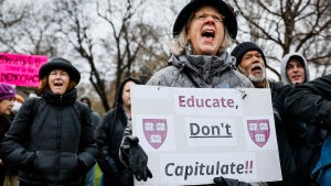 A protester holds a sign reading "Educate, Don't Capitulate!!" during a rally at Cambridge Common (Credit: Erin Clark/The Boston Globe via Getty Images)