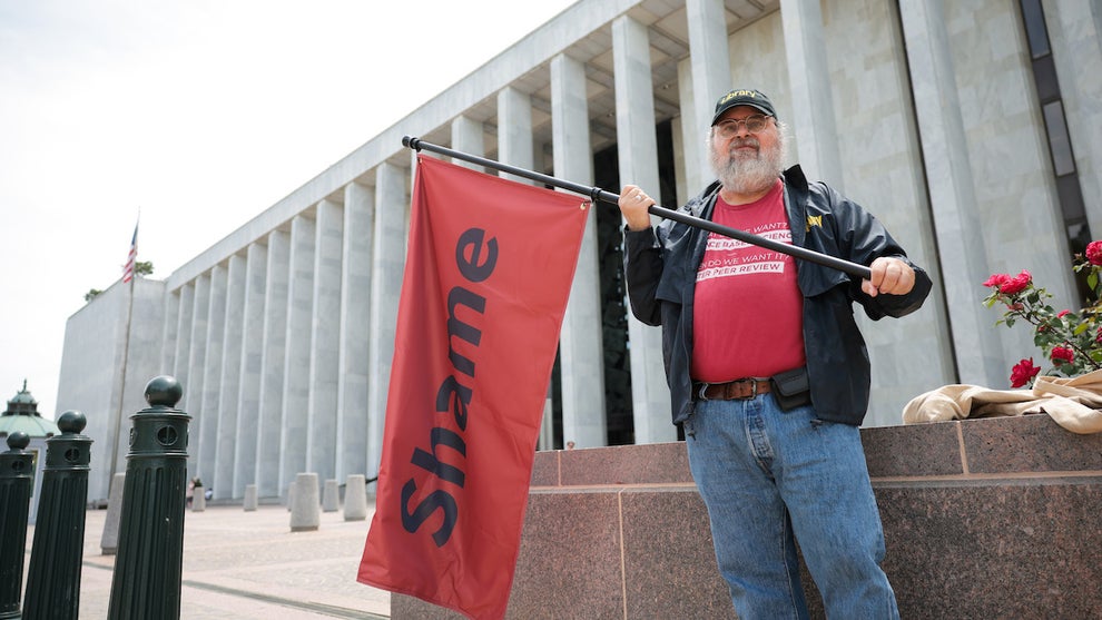 A man holds a flag that reads "Shame" outside the Library of Congress after the head of the Library of Congress and the head of the U.S. Copyright Office were fired by the Trump administration (Credit: Kayla Bartkowski/Getty Images)