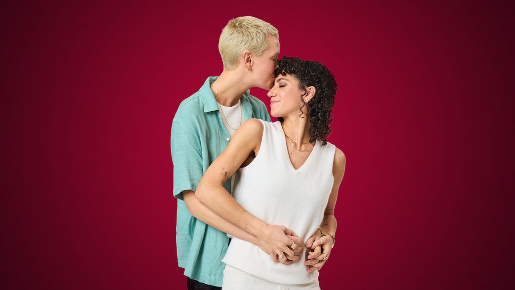 Person kisses another woman on the forehead in front of red background. Kyle and Bridget in Season 2 of "The Ultimatum: Queer Love" (Credit: Melody Timothee / Netflix)