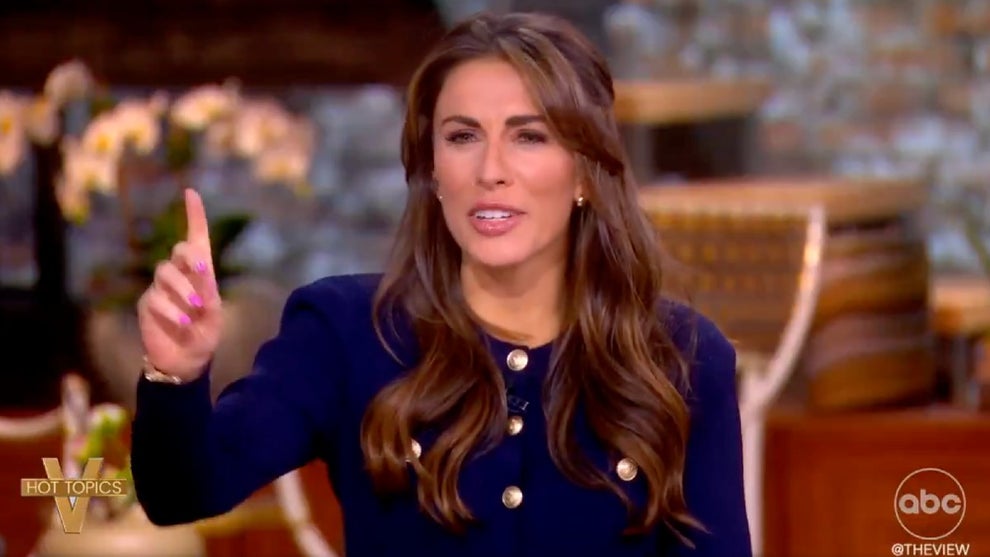Alyssa Farah Griffin, a woman with long brown hair and wearing a blue shirt with gold buttons, holds her finger up in protest