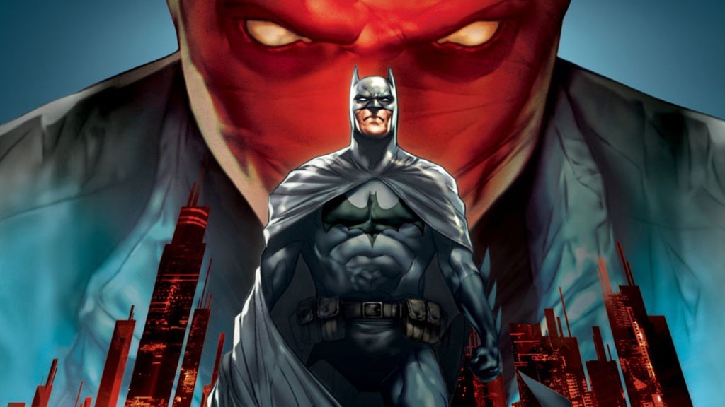Batman stands in front of a city with a man in a red mask looming in the background