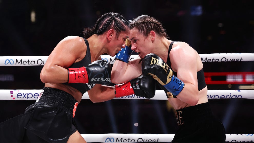 Two female boxers with braided hair clash head-to-head in an intense moment during a match, each wearing gloves and focused expressions inside the ring.