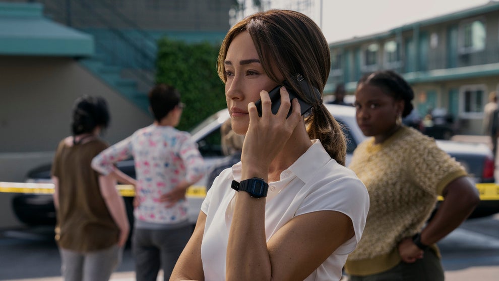 A woman stands outside on a bright day holding a phone to her ear