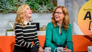 Angela Kinsey and Jenna Fischer, co-hosts of the Office Ladies podcast and former stars of The Office, sit on an orange couch during an interview