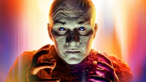 A glowing, bald mutant-like figure with glowing blue eyes and textured skin stares intensely forward with hands raised.