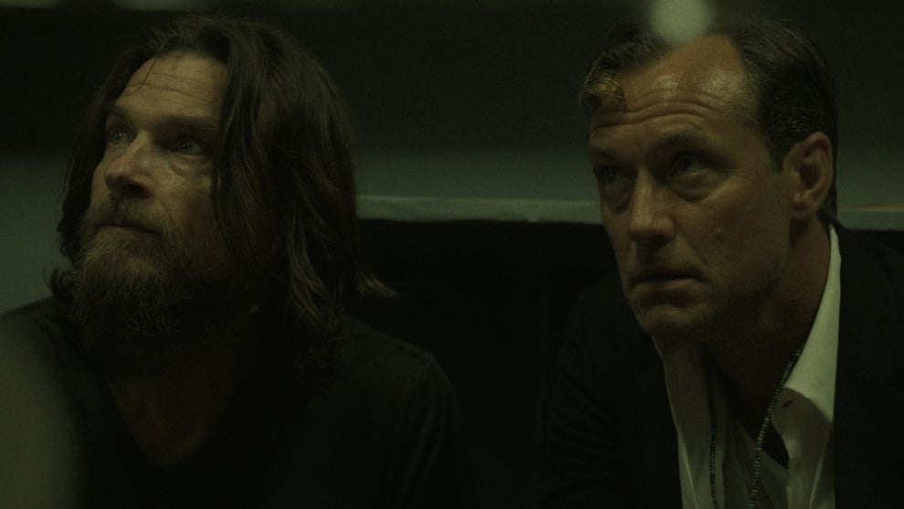 Jason Bateman (left) and Jude Law (right) stare to the left of the frame