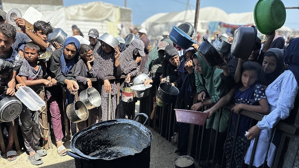 Palestinians, including children, who are struggling to access food due to Israel's blockade and ongoing attacks on the Gaza Strip, wait in line to receive hot meals distributed by the charity organization at Al-Mawasi area in Khan Yunis, Gaza on August 23, 2025