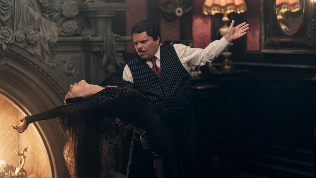 Morticia and Gomez Addams dance as he dips her dramatically in front of a fireplace