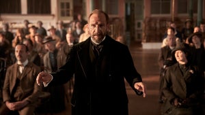 Ralph Fiennes as Dr. Guthrie conducting a choir in front of an intimate crowd a still from "The Choral"