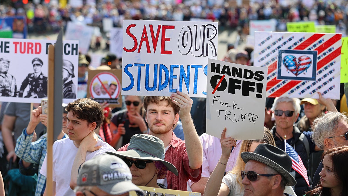 Students protest with signs such as "SAVE OUR STUDNETS" and "HANDS OFF!"