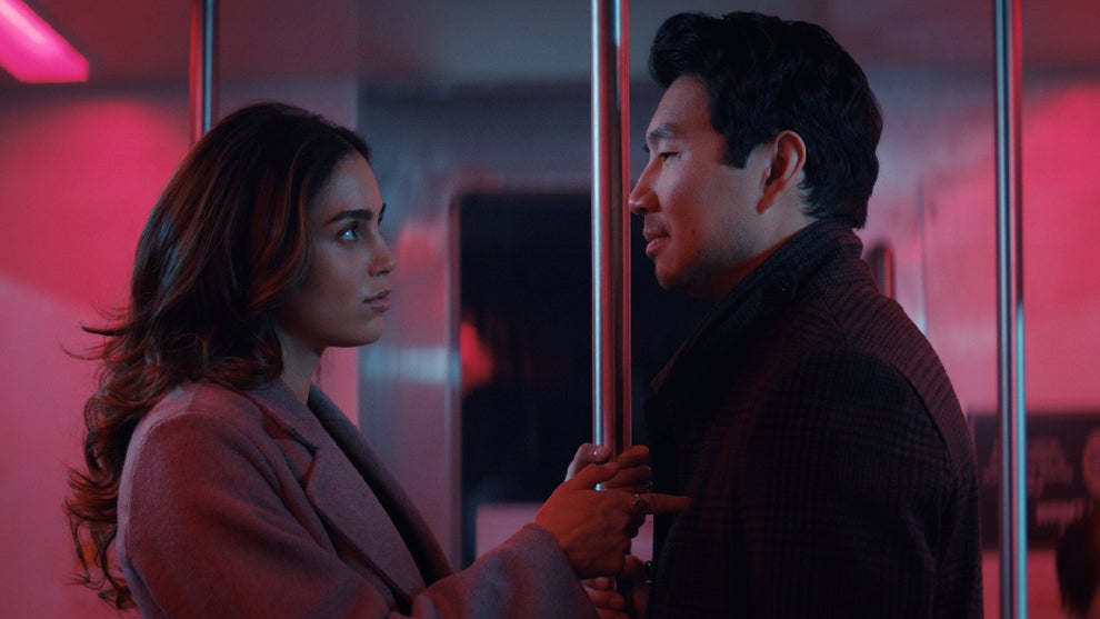 Melissa Barrera (left) and Simu Liu (right) stand under red lighting in "The Copenhagen Test"