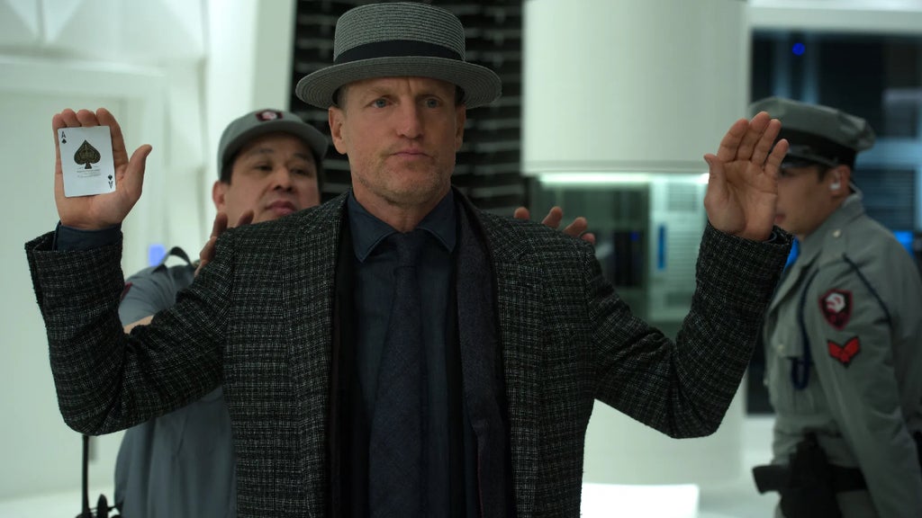 Woody Harrelson palms a card while being checked by a security guard in "Now You See Me 2"