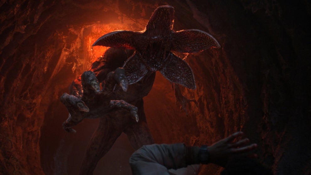 A demogorgon monster attacks against the backdrop of a red-lit cave in Stranger Things Season 5