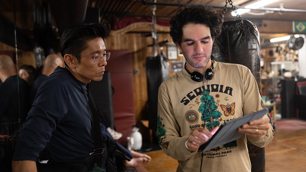Kazu Hiro and Benny Safdie look at a tablet on the set of "The Smashing Machine"