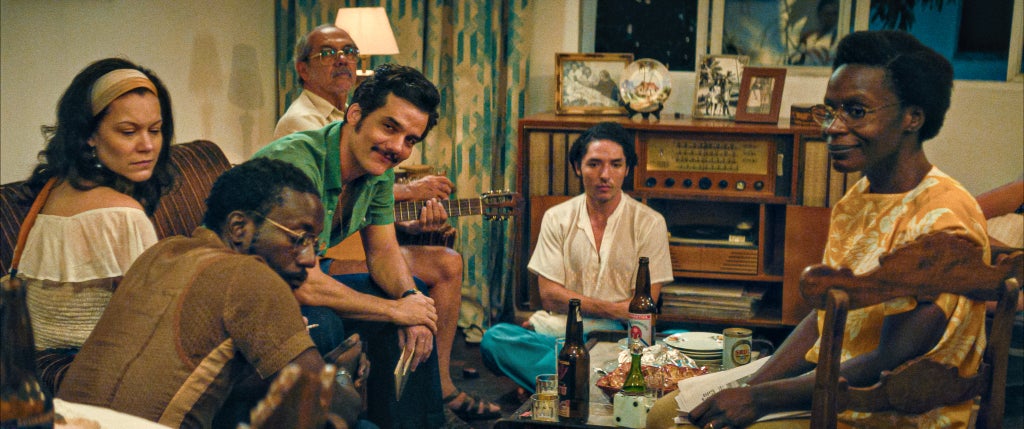 A still from "The Secret Agent" of Armando (Wagner Moura) and other political refugees at  Dona Sebastiana's (Tânia Maria) shelter.