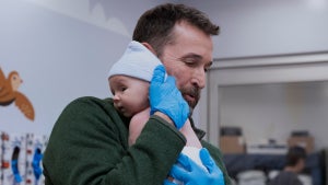 Noah Wiley holds a baby up to his shoulder in "The Pitt" Season 2