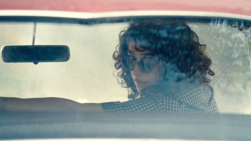 Odessa A'zion sits in a car looking out the back window in sunglasses in "Marty Supreme"
