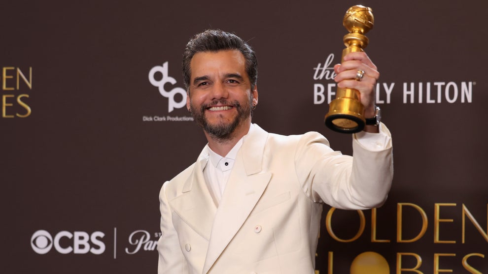 Wagner Moura poses in a white suit with his Golden Globe Flesh of the Gods