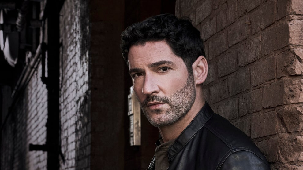 A close-up of Tom Ellis standing against a brick wall in a promotional image for CBS' CIA