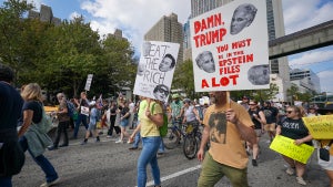 Demonstrators hold protest signs during a march from the Atlanta Civic Center to the Georgia State Capitol on October 18, 2025 in Atlanta, Georgia