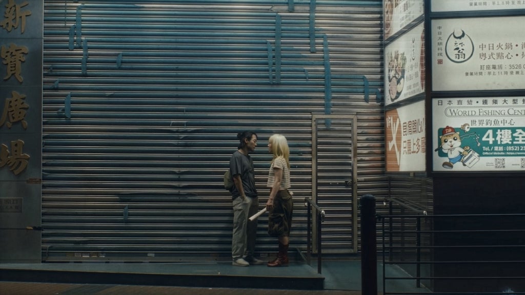 Jin Ha and Haley Lu talk together about something urgent on the streets on Hong Kong in a still from Kogonada's Zi. 