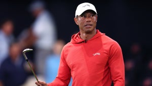 Tiger Woods in a red long sleeve and white hat holding a golf club