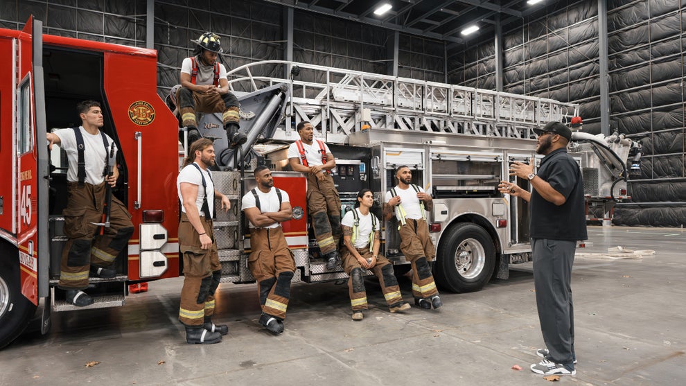 Tyler Perry speaks to the cast of "Where There's Smoke" as they sit/stand on and around a firetruck