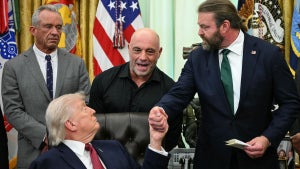 (L/R) US Secretary of Health and Human Services Robert F. Kennedy Jr., and US media personality Joe Rogan look on as US President Donald Trump shakes hands with W. Bryan Hubbard, CEO of Americans for Ibogaine, during an executive order signing ceremony in the Oval Office of the White House in Washington, DC on April 18, 2026. The executive order aims to further US federal medical research and clinical trials for certain psychedelic drugs.certain psychedelic drugs. (Photo by Jim WATSON / AFP via Getty Images)