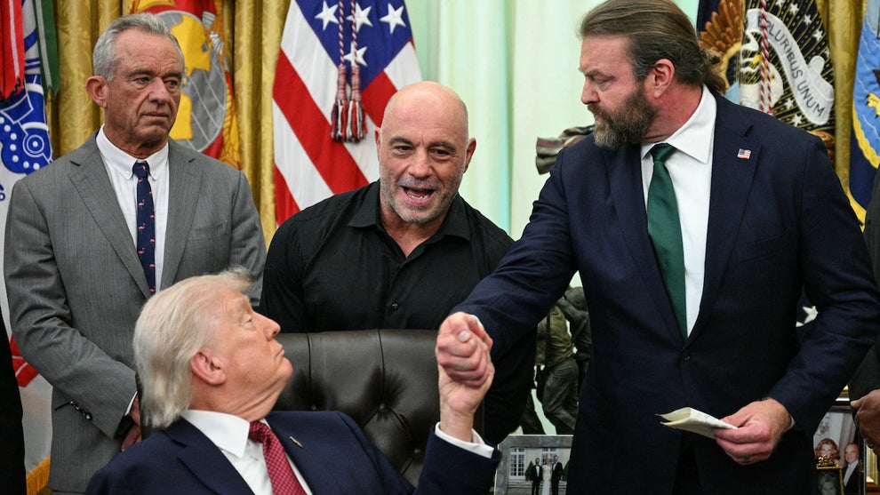 (L/R) US Secretary of Health and Human Services Robert F. Kennedy Jr., and US media personality Joe Rogan look on as US President Donald Trump shakes hands with W. Bryan Hubbard, CEO of Americans for Ibogaine, during an executive order signing ceremony in the Oval Office of the White House in Washington, DC on April 18, 2026. The executive order aims to further US federal medical research and clinical trials for certain psychedelic drugs.certain psychedelic drugs. (Photo by Jim WATSON / AFP via Getty Images)