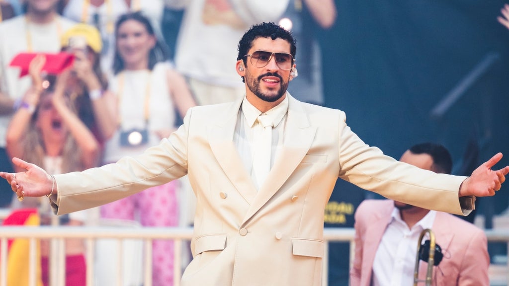 Bad Bunny performs on stage in a white suit