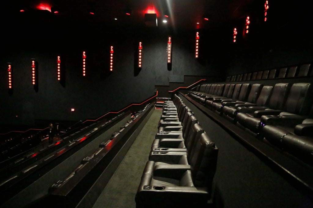 A view of the new Dolby cinema technology in one of the theaters at AMC. All red lights on the numerous bars surround the walls around the full circumference of the theater with hanging speakers on the ceiling above.